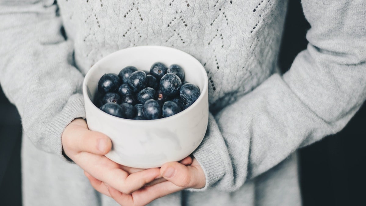 Little girl holding a bowl of blueberries